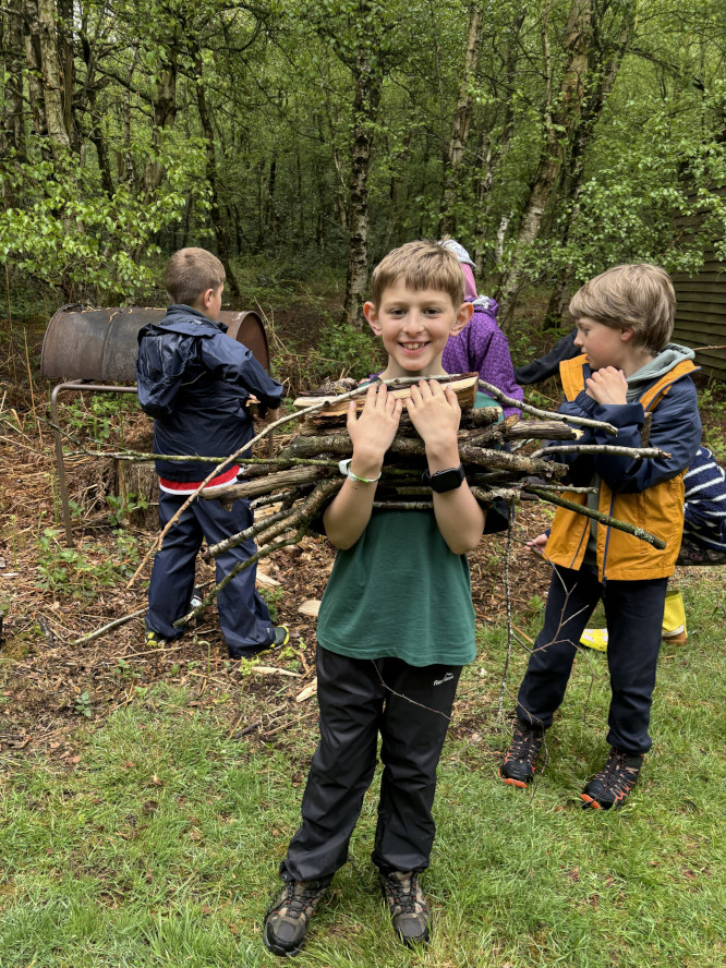 Image of a Cubs smiling and carrying fire wood